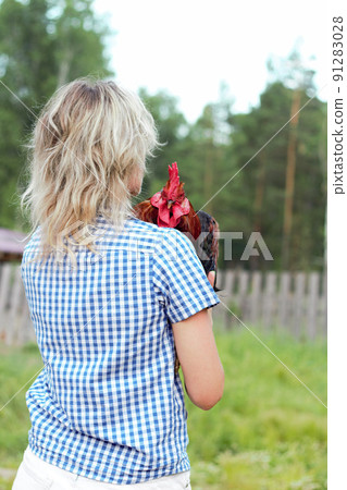 Beautiful woman in the farm holding a chicken, healthy lifestyle 91283028