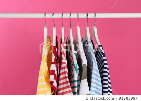 Colorful clothes hanging on rack against pink background 91283987