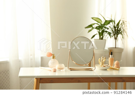 Mirror and makeup products on white table indoors 91284146