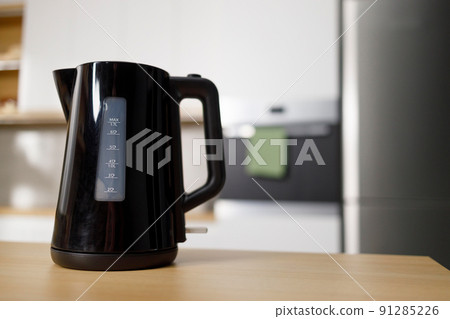 Modern electric kettle on wooden table in kitchen 91285226