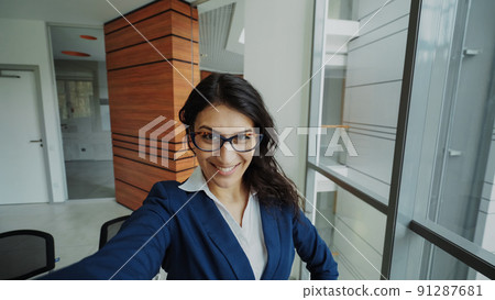 POV of young businesswoman in suit taking a selfie photo holding smartphone and have fun in modern office 91287681
