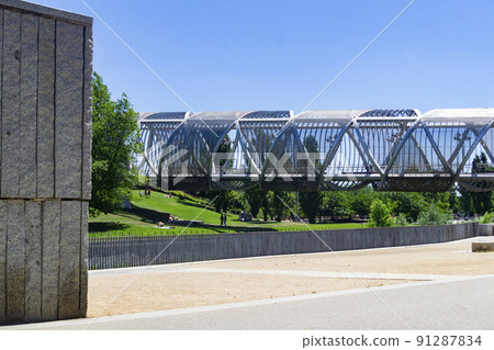 Madrid River Park. Views of the Madrid park next to the Manzanares river and green vegetation around it. Roads with bridges and footbridges. Fountains with water jets, in Spain. Europe. Photography. Madrid River Park. Views of the Madrid park next to the Manzanares river and green vegetation around it. Roads with bridges and footbridges. Fountains with water jets, in Spain. Europe. Photography. 91287834