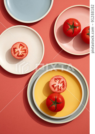 Minimal flatlay of tomato on pastel plates with linen napkin. Flat lay, top view. 91288182