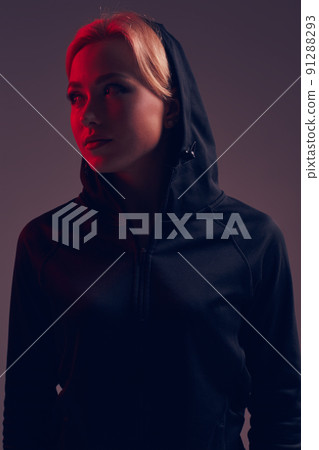 Young pretty woman wearing a black hood and shorts on dark background 91288293