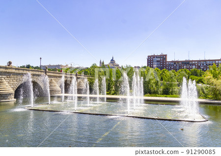 Madrid Rio Park. Views of the Madrid Riv park next to the Manzanares river and green vegetation around it. Roads with bridges and footbridges. Fountains with water jets, in Spain. Europe. Photography. Madrid Rio Park. Views of the Madrid Riv park next to the Manzanares river and green vegetation around it. Roads with bridges and footbridges. Fountains with water jets, in Spain. Europe. Photography. 91290085