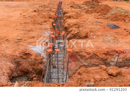 A construction site is being prepared with steel for its foundation by a trench A construction site is being prepared with steel for its foundation by a trench 91291203