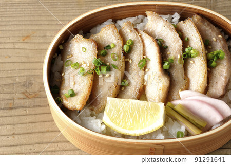 Take a bird's-eye view of a yakiniku bento that contains pickles, cut lemons, and pork jowl in Magewappa. 91291641