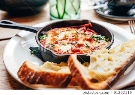 Shakshuka in iron pan served with bread 91292119