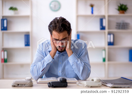 Young male call center operator working at his desk Young male call center operator working at his desk 91292359