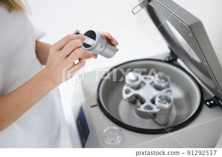 Cosmetologist puts tube of blood in centrifuge. Plasmolifting procedure. Preparation of blood for injections. Cosmetologist puts tube of blood in centrifuge. Plasmolifting procedure. Preparation of blood for injections. 91292517