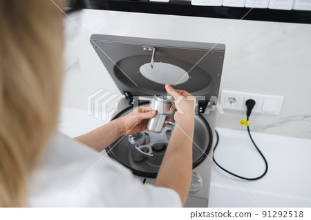 Doctor beautician puts a test tube in a metal container. Preparation for the plasmolifting procedure Doctor beautician puts a test tube in a metal container. Preparation for the plasmolifting procedure 91292518