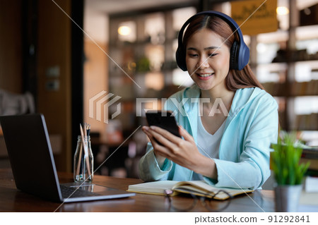 photo of woman wearing headphones and using mobile phone for online learning - educational course or training, seminar, education online concept photo of woman wearing headphones and using mobile phone for online learning - educational course or training, seminar, education online concept 91292841