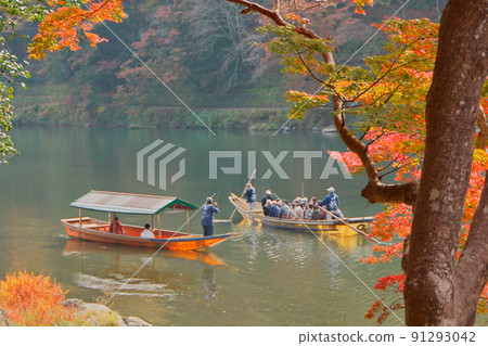 一艘沿著保津川下行的觀光船經過桂川岸邊楓樹附近的一艘船屋。 91293042