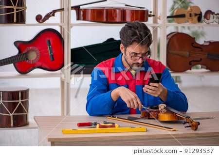 Young man repairing musical instruments at workshop 91293537