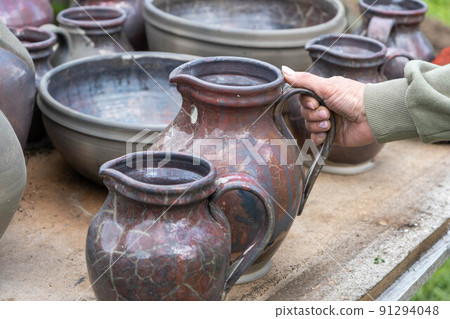 fired earthenware removed from the kiln. The woman looks at the outcome. Mugs, pots, plates and everything else beautiful and useful. Latvian national cultural heritage 91294048