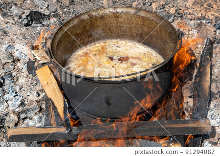 Close up of stewed beef meat in cooking pot with herbs, spices and kitchen utensils, top view. Country's meat dishes. Slow cooking. Rustic food 91294087