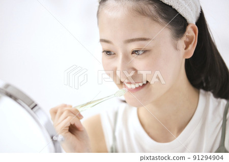 一個年輕女子在照鏡子時刷牙 91294904
