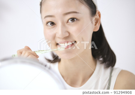 一個年輕女子在照鏡子時刷牙 91294908