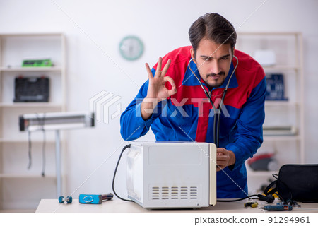 Young male repairman repairing oven at workshop 91294961