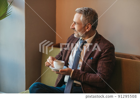Meditating man with coffee sitting sideways to camera Meditating man with coffee sitting sideways to camera 91295508