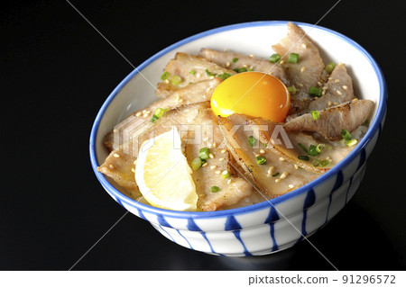 Pork toro bowl with cut lemon and egg yolk, grilled meat bowl photographed on a black background 91296572