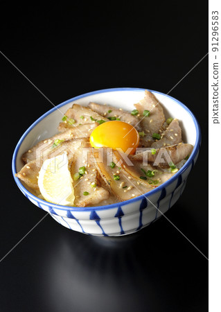 Pork toro bowl with cut lemon and egg yolk, grilled meat bowl photographed on a black background Pork toro bowl with cut lemon and egg yolk, grilled meat bowl photographed on a black background 91296583