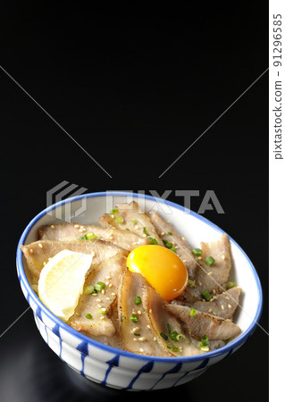 Pork toro bowl with cut lemon and egg yolk, grilled meat bowl photographed on a black background 91296585