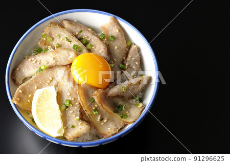 A bird's-eye view of a pork bowl with cut lemon and egg yolk and a grilled meat bowl on a black background 91296625