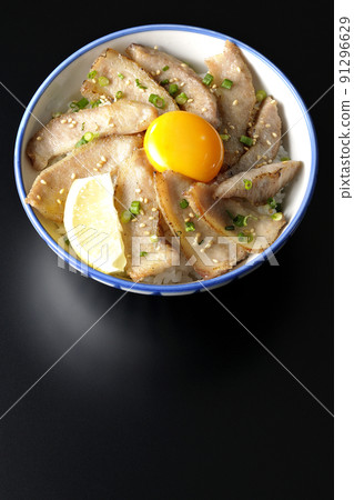 A bird's-eye view of a pork bowl with cut lemon and egg yolk and a grilled meat bowl on a black background A bird's-eye view of a pork bowl with cut lemon and egg yolk and a grilled meat bowl on a black background 91296629