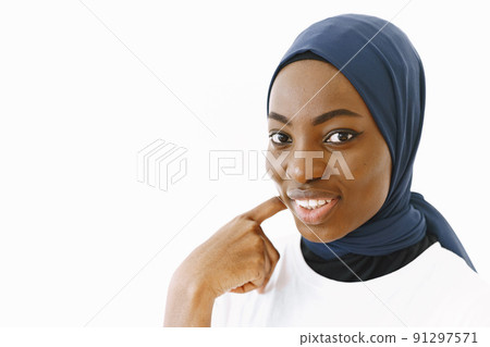 Headshot of lovely satisfied religious Muslim woman with gentle smile, dark healthy skin, wears scarf on head. Isolated over white background. 91297571