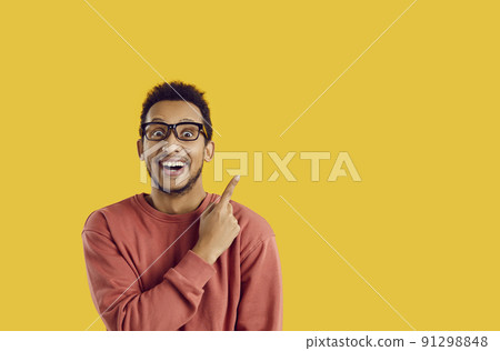 Happy excited university student pointing his finger to the side on copy space background Happy excited university student pointing his finger to the side on copy space background 91298848