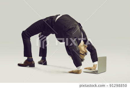 Happy flexible businessman in suit doing yoga while working on his laptop computer Happy flexible businessman in suit doing yoga while working on his laptop computer 91298850