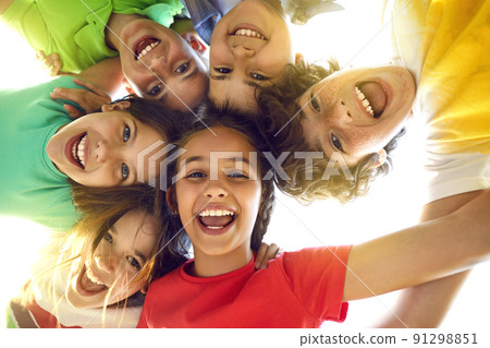 Group of happy little children playing together, having fun, huddling, looking down and smiling 91298851