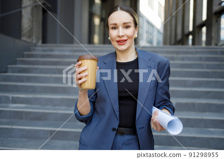 Portrait of business woman with rolled up paper outdoors Portrait of business woman with rolled up paper outdoors 91298955