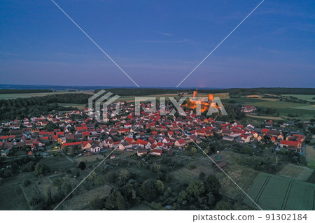 Drone image of Muenzenberg with illuminated castle ruins in Germany Drone image of Muenzenberg with illuminated castle ruins in Germany 91302184