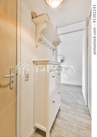 Light narrow hallway with many doors in white walls and glowing lamp over lumber floor 91302241