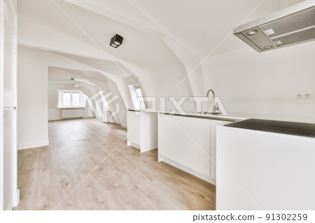 Spacious attic room of apartment with open kitchen under roof with beams Spacious attic room of apartment with open kitchen under roof with beams 91302259