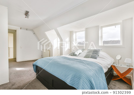 Home interior design of bedroom with bed and wooden wardrobe placed in corner near window in modern apartment 91302399