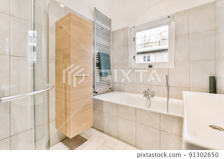Sinks with mirrors and clean bathtub located near shower box with glass door in modern bathroom with white tiled walls 91302650