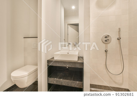 Sink and mirror located near flush toilet and bathtub against concrete wall 91302681