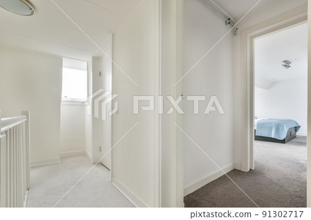 Closed white door of room located near framed pictures and stylish lamp on top of stairway at home Closed white door of room located near framed pictures and stylish lamp on top of stairway at home 91302717