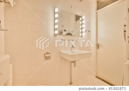 Flush toilet located between sink and shower in small tiled bathroom of contemporary apartment 91302871
