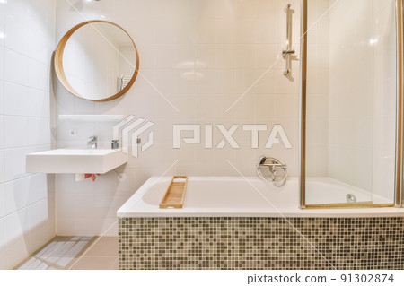 Interior of white tiled bathroom with circle mirror 91302874