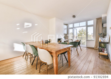 Wooden table with chairs and vase located near drinks rack against light walls and computer desk near the fireplace Wooden table with chairs and vase located near drinks rack against light walls and computer desk near the fireplace 91302894