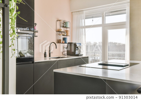 Wooden dining table under pendant lamp in open plan kitchen with living room Wooden dining table under pendant lamp in open plan kitchen with living room 91303014