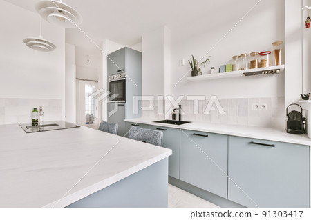 Home interior design of modern loft apartment with open kitchen in minimalist style and spacious dining zone with table and chairs Home interior design of modern loft apartment with open kitchen in minimalist style and spacious dining zone with table and chairs 91303417