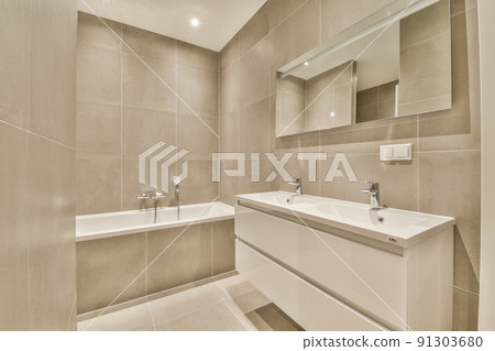 Sink with tap and liquid soap hanging on tiled wall under mirror in contemporary restroom at home 91303680