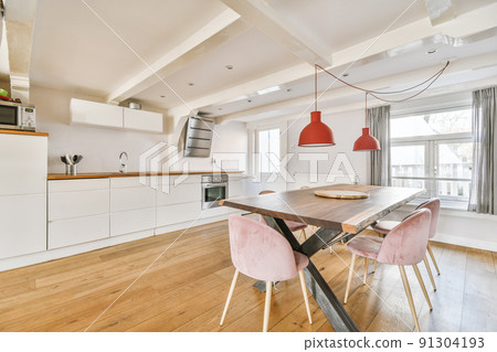 Home interior design of modern loft apartment with open kitchen in minimalist style and spacious dining zone with table and chairs Home interior design of modern loft apartment with open kitchen in minimalist style and spacious dining zone with table and chairs 91304193