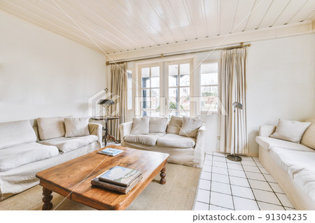 Table with chairs near lounge area and kitchen in spacious room of contemporary apartment Table with chairs near lounge area and kitchen in spacious room of contemporary apartment 91304235
