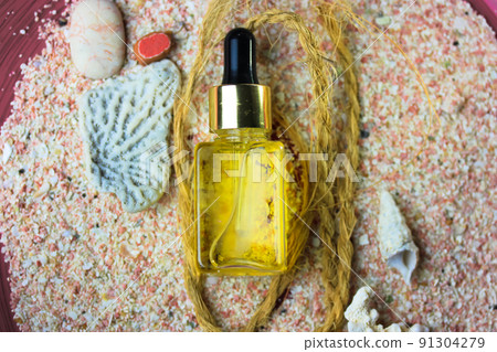 Sunscreen oil for protection against sunburns on summer vacation at sea beach, ocean shore. Cosmetics for the beach. Transparent glass or plastic jar, container of yellow oil to moisturize face, body. Sunscreen oil for protection against sunburns on summer vacation at sea beach, ocean shore. Cosmetics for the beach. Transparent glass or plastic jar, container of yellow oil to moisturize face, body. 91304279